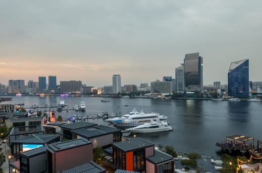 View along the Creek towards Deira with large boats docked by the Al Seef boardwalk in Dubai, UAE