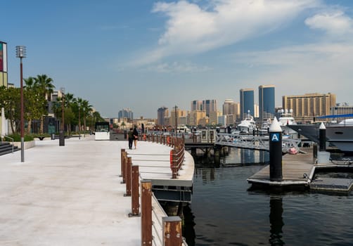 View along the Creek towards Deira with large boats docked by the Al Seef boardwalk in Dubai, UAE