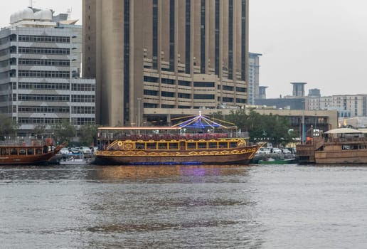 View along the Creek towards Deira with large dhow tour boats docked by the Al Seef boardwalk in Dubai, UAE