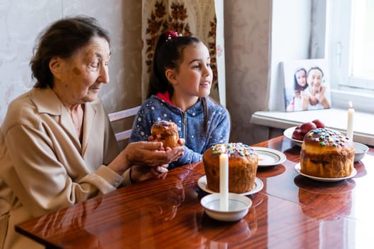 Easter concept. Grandmother with granddaughter are holding Easter eggs at home.