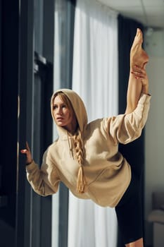 Posing for the camera. Woman in sportive clothes doing yoga indoors.