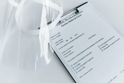 Close up view of protective mask and medical agreement that is on the white table.