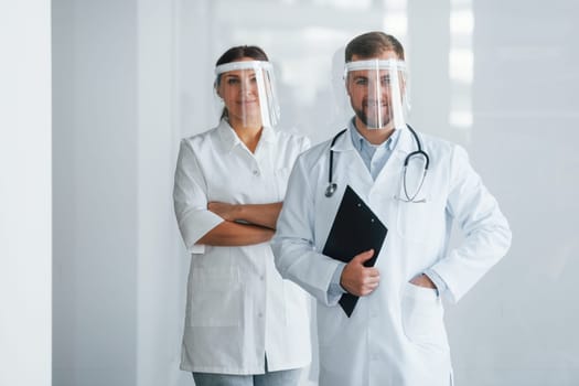 Front view. Two doctors in white coats is in the clinic working together.