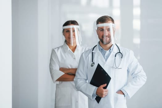 Front view. Two doctors in white coats is in the clinic working together.