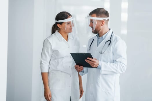 Front view. Two doctors in white coats is in the clinic working together.