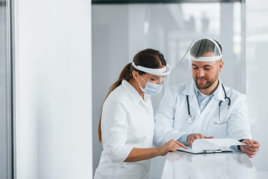 Working with documents. Two doctors in white coats is in the clinic.