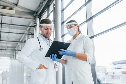 Working with documents. Two doctors in white coats is in the clinic.