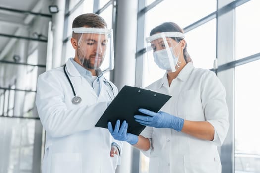 Working with documents. Two doctors in white coats is in the clinic.