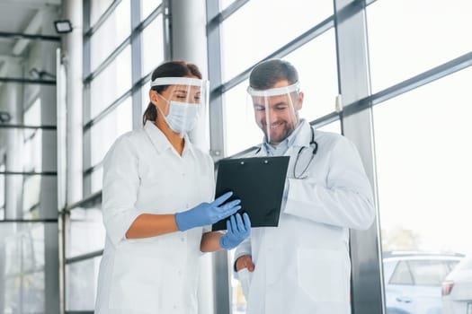 Busy people. Two doctors in white coats is in the clinic working together.