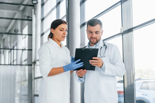 Busy people. Two doctors in white coats is in the clinic working together.