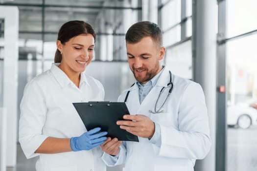 Having busy day. Two doctors in white coats is in the clinic working together.