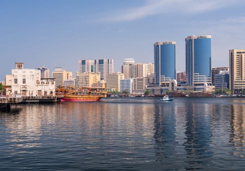 Dubai, UAE - 31 March 2023: View along the Creek towards Deira with large dhow tour boats docked by the Al Seef boardwalk