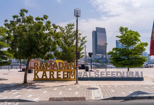 Dubai, UAE - 31 March 2023: View across the Creek towards Deira with hashtag sign for Ramadan on the Al Seef boardwalk