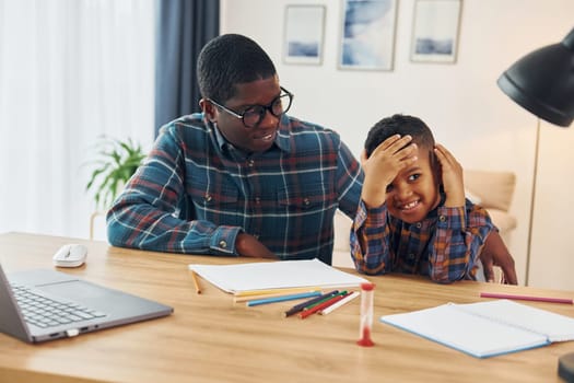 Cheerful family. African american father with his young son at home.