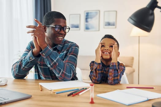 Cheerful family. African american father with his young son at home.