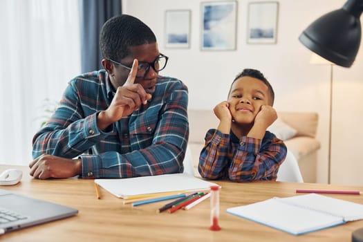 Cheerful family. African american father with his young son at home.