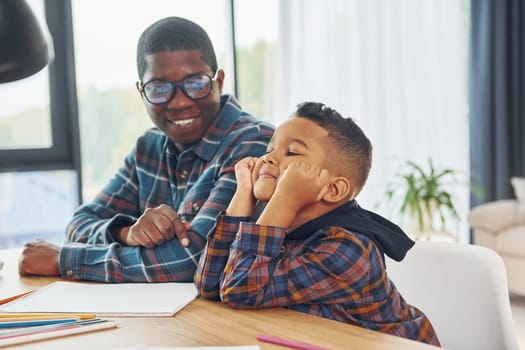 Cheerful family. African american father with his young son at home.