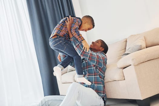 Active weekend time spending. African american father with his young son at home.