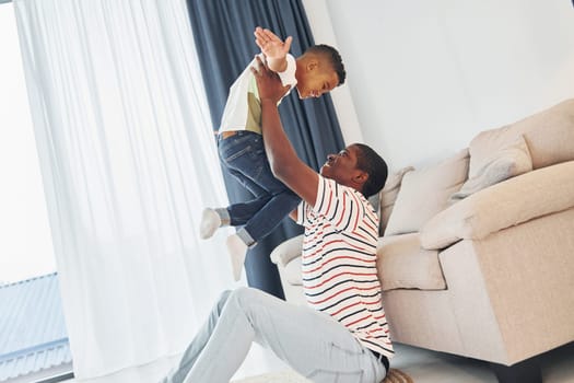 Active weekend time spending. African american father with his young son at home.
