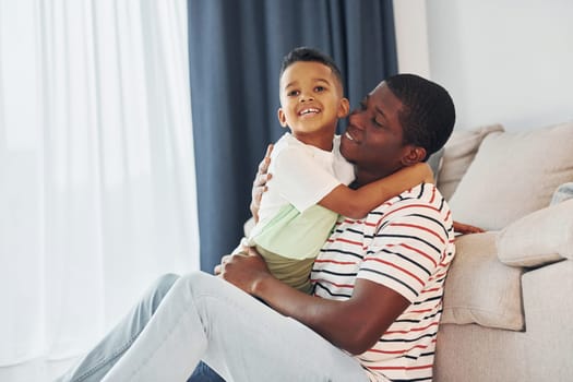 Active weekend time spending. African american father with his young son at home.