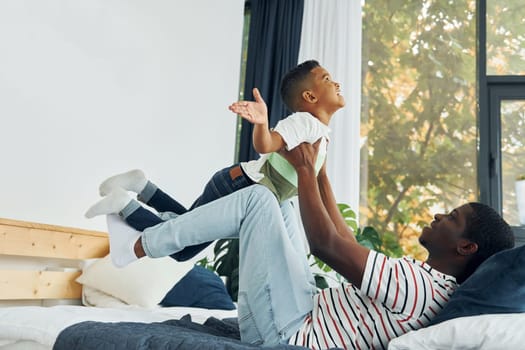 In domestic room. African american father with his young son at home.