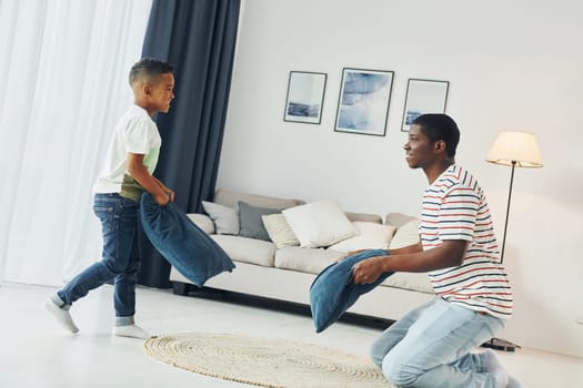 Pillow fight. African american father with his young son at home.