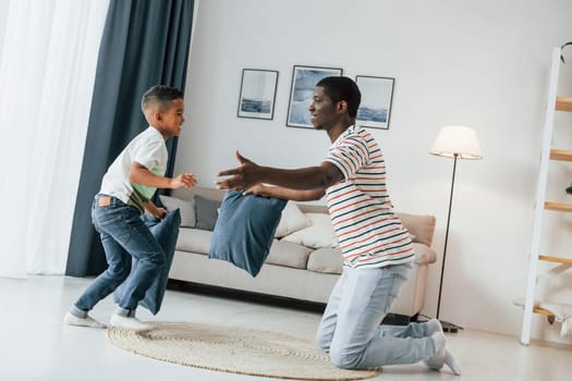 Pillow fight. African american father with his young son at home.