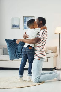 Holding pillows. African american father with his young son at home.