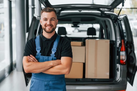 Portrait of delivery man in uniform that is indoors with car and with order.