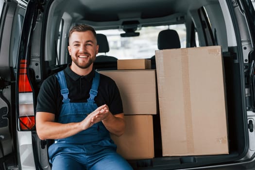 Portrait of delivery man in uniform that is indoors with car and with order.