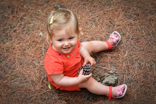 Little girl holding a cone in the woods