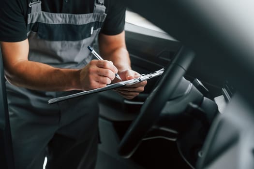 Man in uniform is working in the autosalon at daytime.