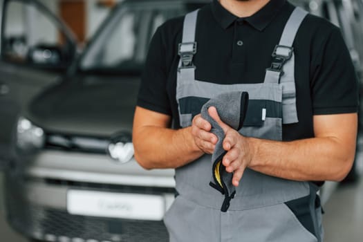 Man in uniform is working in the autosalon at daytime.