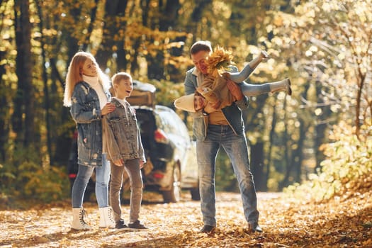 Front view. Happy family is in the park at autumn time together.