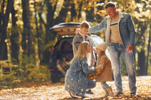 Front view. Happy family is in the park at autumn time together.
