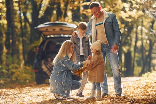 Front view. Happy family is in the park at autumn time together.