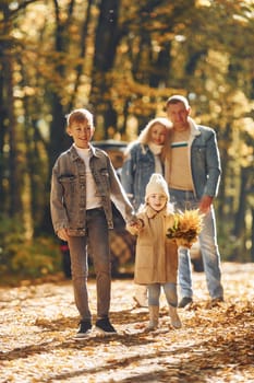 Front view. Happy family is in the park at autumn time together.