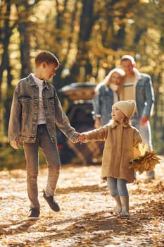 Sister with brother walking. Happy family is in the park at autumn time together.