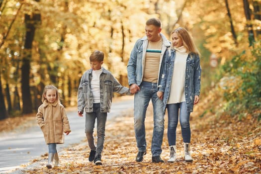 Four people. Happy family is in the park at autumn time together.