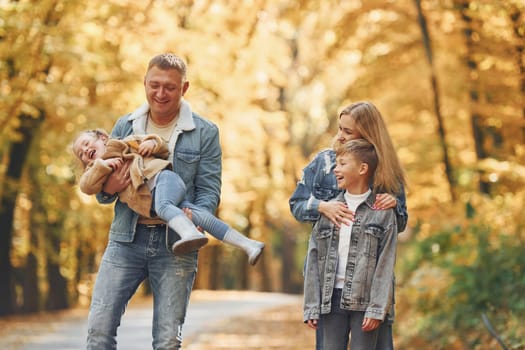 Four people. Happy family is in the park at autumn time together.