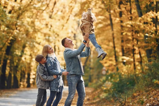 Four people. Happy family is in the park at autumn time together.