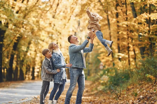 Four people. Happy family is in the park at autumn time together.