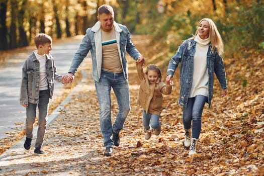 Near the road. Happy family is in the park at autumn time together.