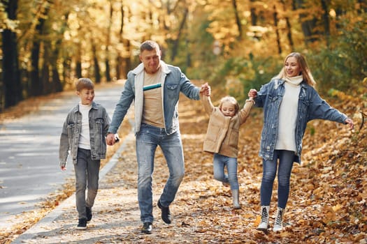 Near the road. Happy family is in the park at autumn time together.