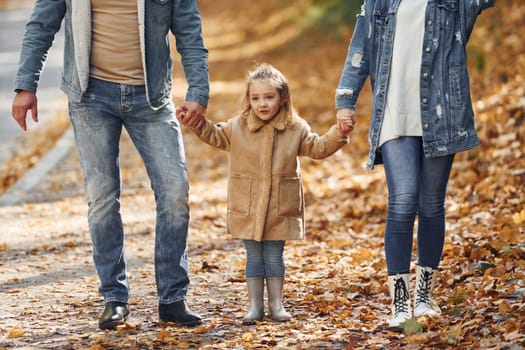 Near the road. Happy family is in the park at autumn time together.