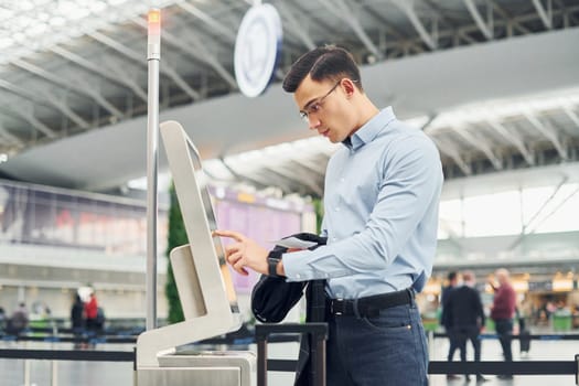 Young male passanger in formal clothes is in the airport.