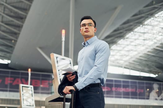 Young male passanger in formal clothes is in the airport.