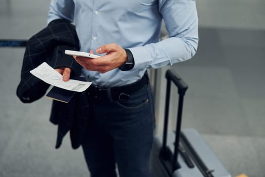 Young male passanger in formal clothes is in the airport.