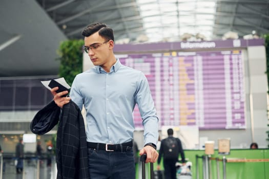 Young male passanger in formal clothes is in the airport.