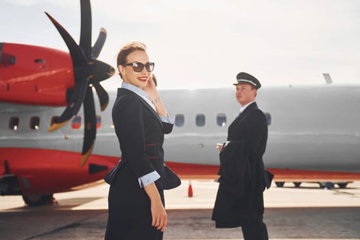 Pilot and stewardess. Crew of airport and plane workers in formal clothes standing outdoors together.